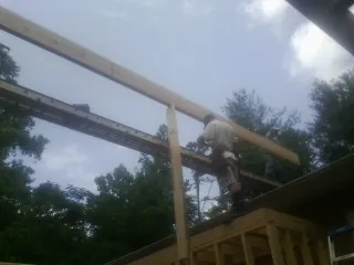 Carpenter setting a ridge beam over a new addition frame — Ice Dam Removal by Roofing Brothers in Braintree