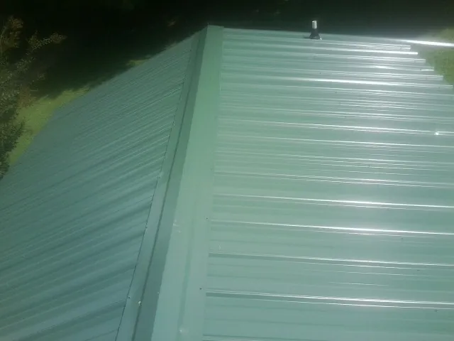 New green metal panels meeting at the ridge of a roof — Flat Roof Repair work by our crew in Braintree