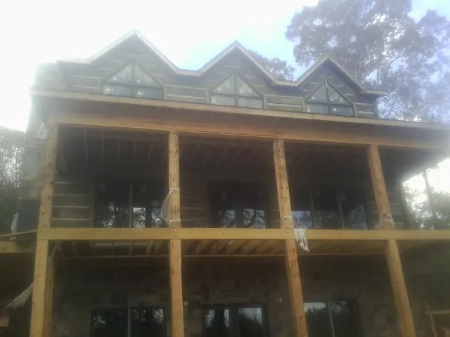 Dormers and porch framing on a large log home under construction — Roof Coating work by our crew in Braintree