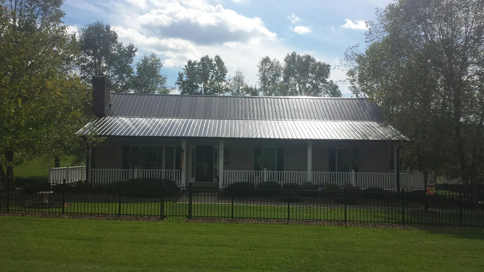 Gray metal roof on a brick ranch with a full width front porch — Gutter Guard Installation work by our crew in Braintree