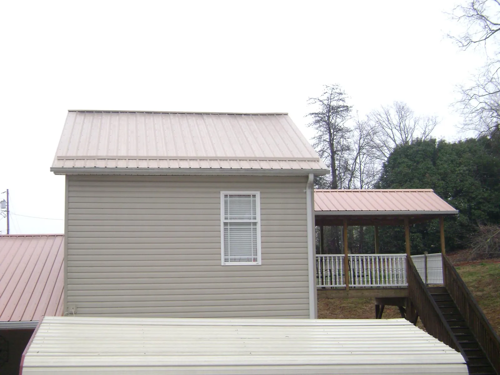 Tan metal roofs on a two story addition and attached porch, from a Roof Replacement job in Braintree